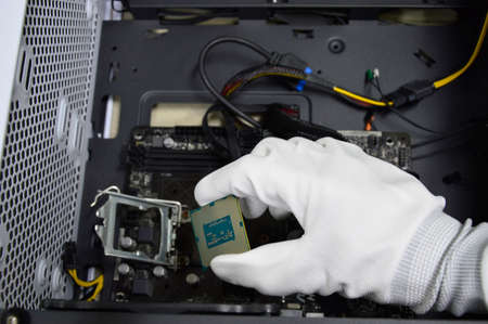 Image of a technician inserting a CPU chip onto a computer motherboard.の写真素材