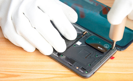 Image of a technician screwing the back of a mobile phoneの写真素材