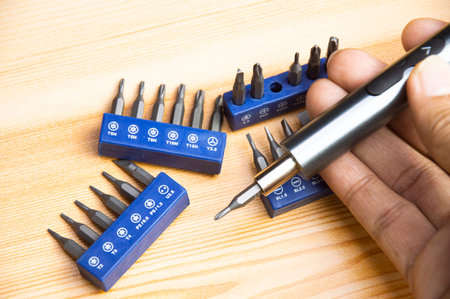 Picture of a mini electric screwdriver, interchangeable tip, placed on a wooden floor.の写真素材