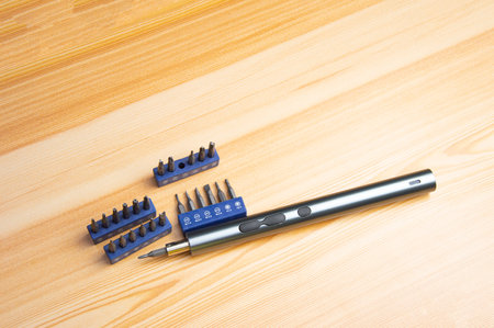 Picture of a mini electric screwdriver, interchangeable tip, placed on a wooden floor.の写真素材
