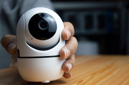 White ip camera lies on wooden floor, man using ip cameraの写真素材