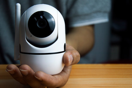 White ip camera lies on wooden floor, man using ip cameraの写真素材