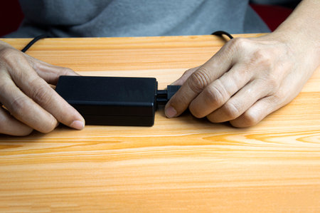 Man plugging into a black power adapterの写真素材