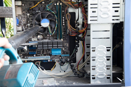 Photograph of a technician blowing dust from a computerの写真素材