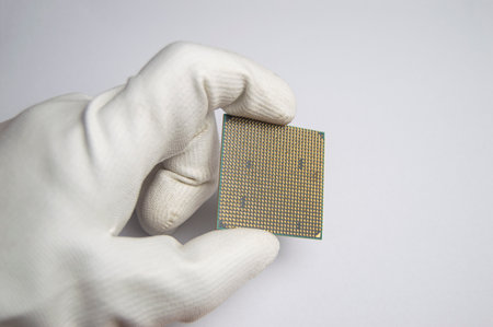 Picture of CPU chip in hand, CPU with many pins, on white background.