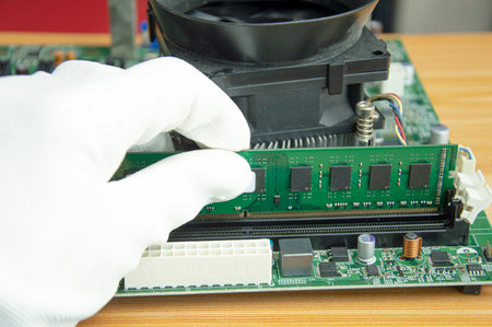 Side view of a technician clearing the RAM of a computer motherboard.の写真素材