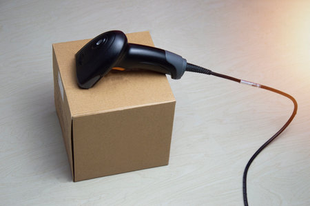 A barcode scanner is placed on a brown box.の写真素材