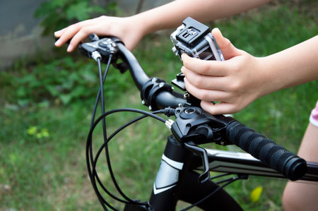 A woman's hand adjusts a digital camera mounted on the handlebars of a mountain bike.の写真素材