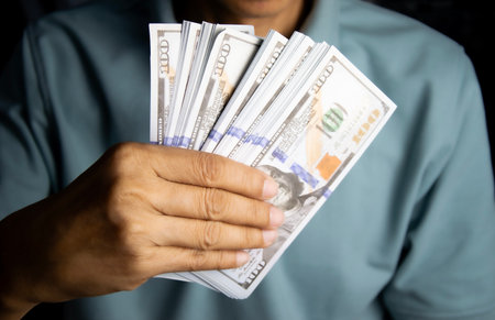 Hand holding money, one hundred dollar bill in man's hand to pay and give.