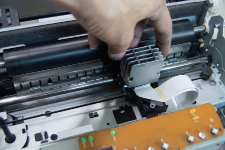 Top view of technician inspecting and repairing printer.
