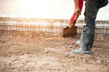 Workers are using shovels to level the ground before pouring concrete at a road construction site.