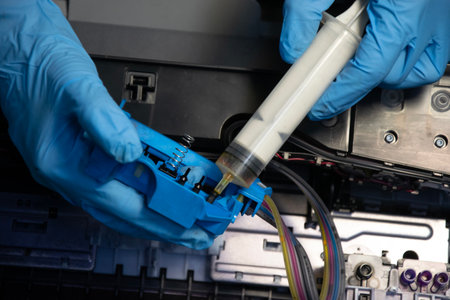 Top view of a technician using a vacuum cleaner to suck ink from a printer.