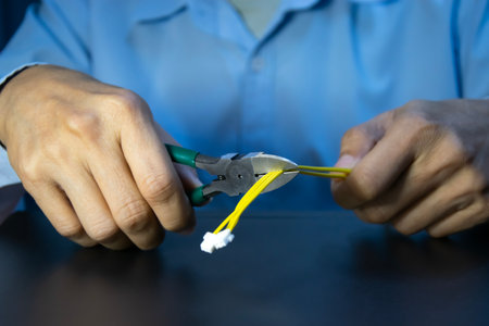 A male technician is using yellow wire cutters.の写真素材