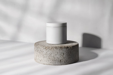 White cosmetic bottle on concrete pedestal on white background with shadows.の素材