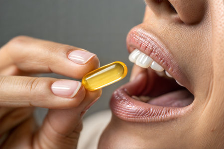 Close-up of a woman taking a vitamin capsule from her mouthの写真素材