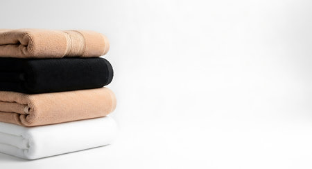 Stack of folded beige and black towels on a white background.の写真素材