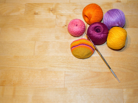 crocheting in progress and colorful cotton thread balls on the wooden background with spaceの写真素材