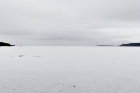 Minimalistic monochrome winter shot of a lake featuring symmetric compositionの写真素材