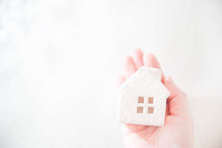 A house wrapped in a hand. Bright image of real estate, home, family, life etc.の写真素材