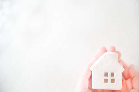 A house wrapped in a hand. Bright image of real estate, home, family, life etc.の写真素材