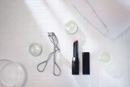 Red lipstick and eyelash curler for lip makeup. Image of cosmetics, cosmetics, and beauty.