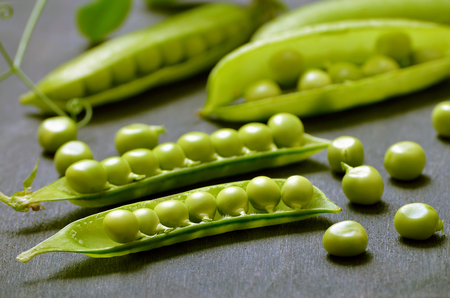 Fresh pods of peas on dark wooden table, close upの写真素材