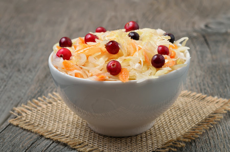 Sauerkraut and cranberries in white bowl on wooden tableの写真素材
