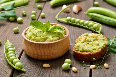 Sandwiches with green pea puree and pine nuts. Green pea puree in wooden bowl. Fresh green peasの写真素材