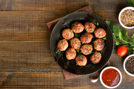 Fried meatballs in cast iron pan on wooden table, top viewの写真素材