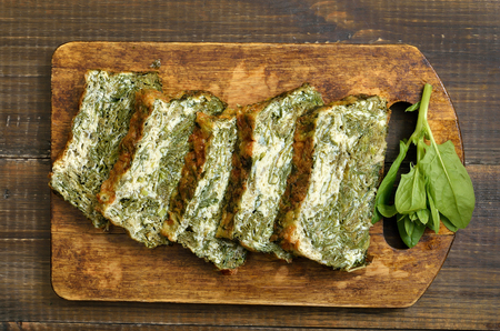 Slices of homemade spinach bread on wooden cutting board, top viewの写真素材