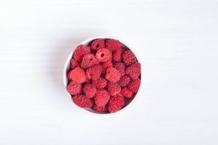 Raspberries in  bowl on white background, top view