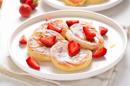 Homemade pancakes with cottage cheese and strawberry slices, healthy breakfast, close up view