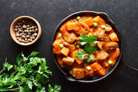 Beef stew with potatoes and carrots in tomato sauce on black background with copy space.  Top view, flat layの写真素材