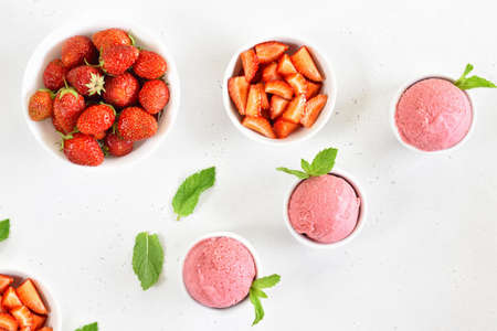 Strawberry ice cream scoop in bowl on white stone background. Top view, flat lay