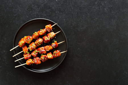 Teriyaki chicken skewers on plate over black background. Top view, flat layの写真素材