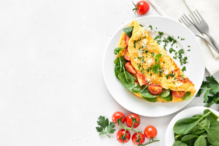 Stuffed omelette with tomatoes and spinach over light stone background with copy space. Top view, flat layの写真素材