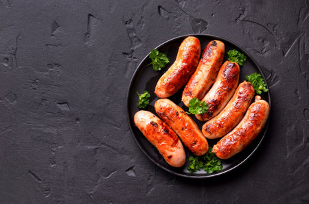 Barbecue bratwurst on plate over black stone background with copy space. Top view, flat layの写真素材