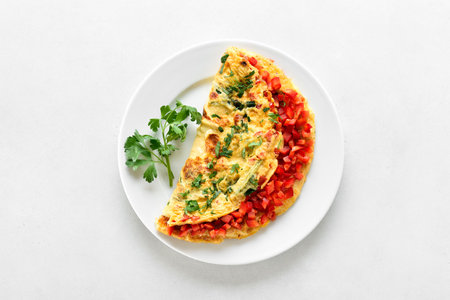 Stuffed omelette with red bell pepper and green onion on plate. Top view, flat layの写真素材