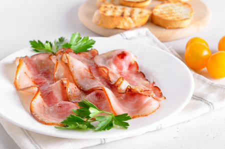 Fried bacon slices on white plateの写真素材