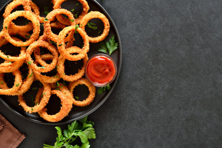 Onion rings owe dark background with copy space. Top view, flat layの写真素材