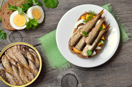 Fish sandwich with sprats and eggs over wooden background. Top view, flat layの写真素材