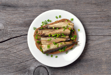 Fish sandwich with sprats over wooden background. Top view, flat layの写真素材