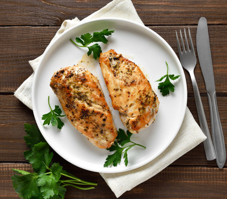 Roasted chicken breast on plate over wooden background. Top view, flat layの写真素材