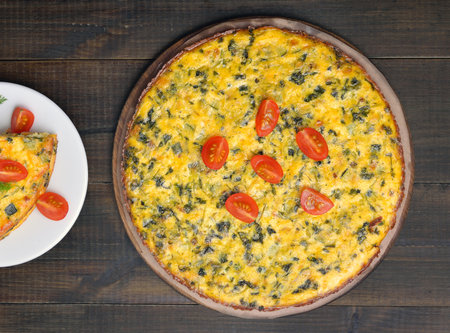 Omelet with herbs and fresh tomatoes over wooden background. Top view, flat lay