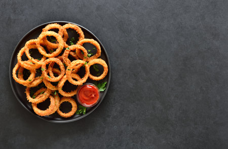 Onion rings owe dark background with copy space. Top view, flat layの写真素材