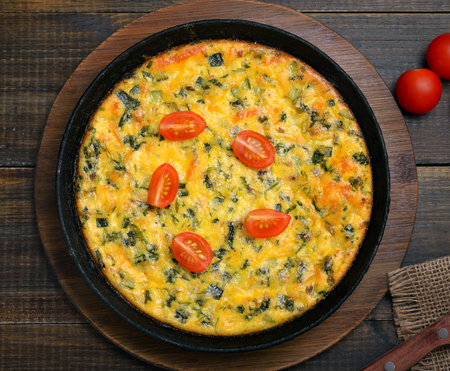 Omelet with herbs and fresh tomatoes over wooden background. Top view, flat layの写真素材