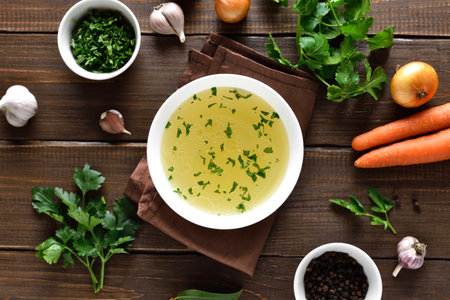Chicken broth with vegetables and spices on wooden background. Top view, flat layの写真素材