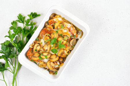 Stewed chicken breast with creamy mushroom sauce on white stone background with copy space. Top...