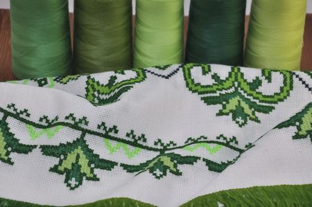 Traditional Ukrainian embroidered towel bright green thread in the hoop on the background of a wooden tableの写真素材