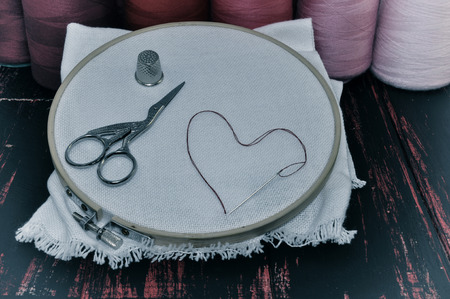 Vintage photos of objects for needlework in red tones on the old wooden tableの写真素材